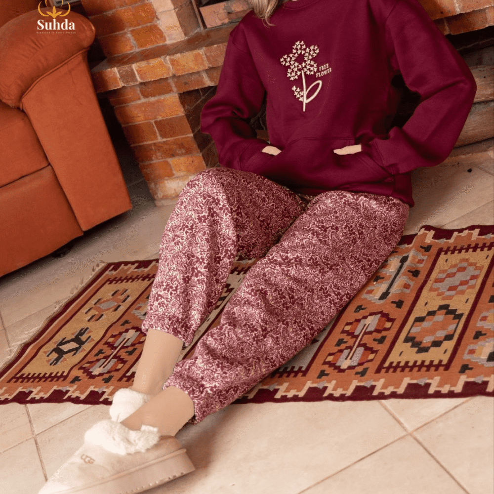 طقم شتوي نسائي بلون عودي يضم جاكت بجيب أمامي وبنطال منقوش، مناسب للارتداء داخل المنزل.