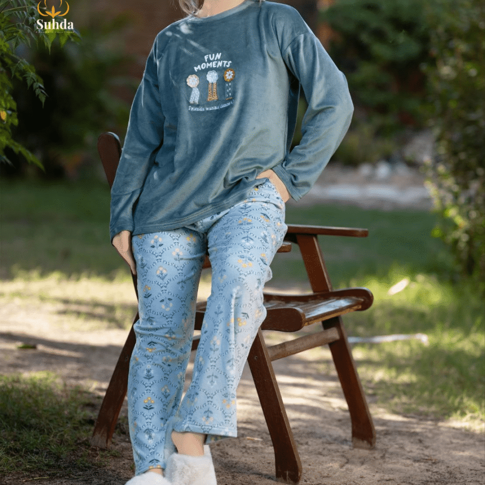 طقم شتوي نسائي يتكون من بلوزة مخملية سماوية اللون مع طبعة أمامية وبنطال منقوش فاتح.