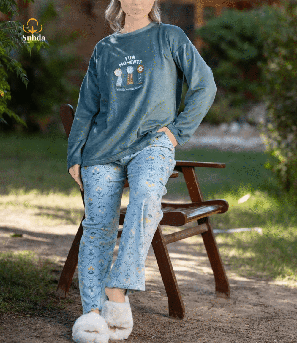 طقم شتوي نسائي يتكون من بلوزة مخملية سماوية اللون مع طبعة أمامية وبنطال منقوش فاتح.