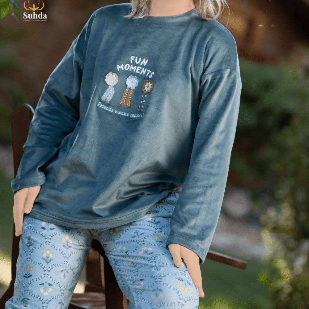 طقم شتوي نسائي يتكون من بلوزة مخملية سماوية اللون مع طبعة أمامية وبنطال منقوش فاتح.