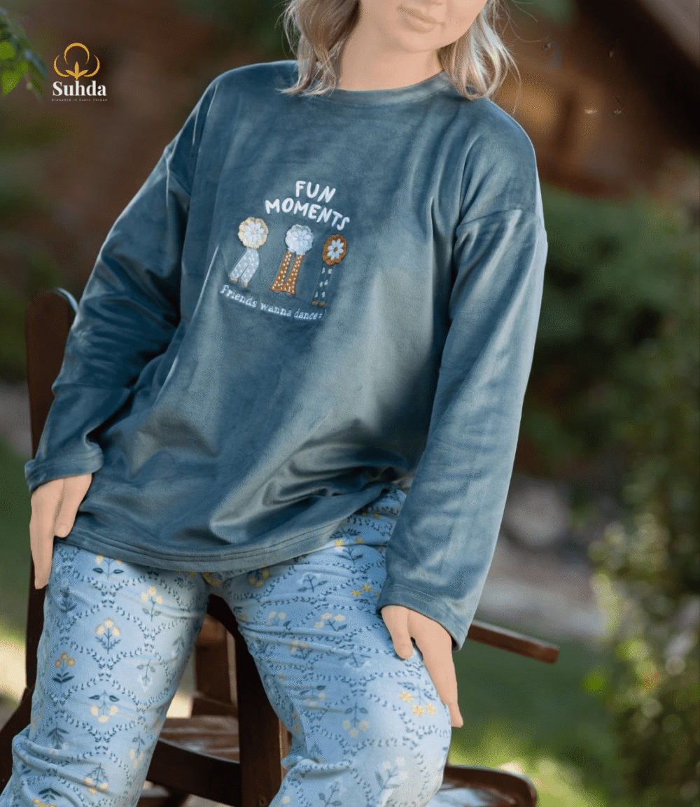 طقم شتوي نسائي يتكون من بلوزة مخملية سماوية اللون مع طبعة أمامية وبنطال منقوش فاتح.