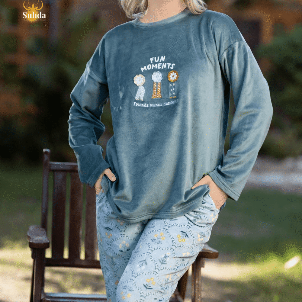 طقم شتوي نسائي يتكون من بلوزة مخملية سماوية اللون مع طبعة أمامية وبنطال منقوش فاتح.