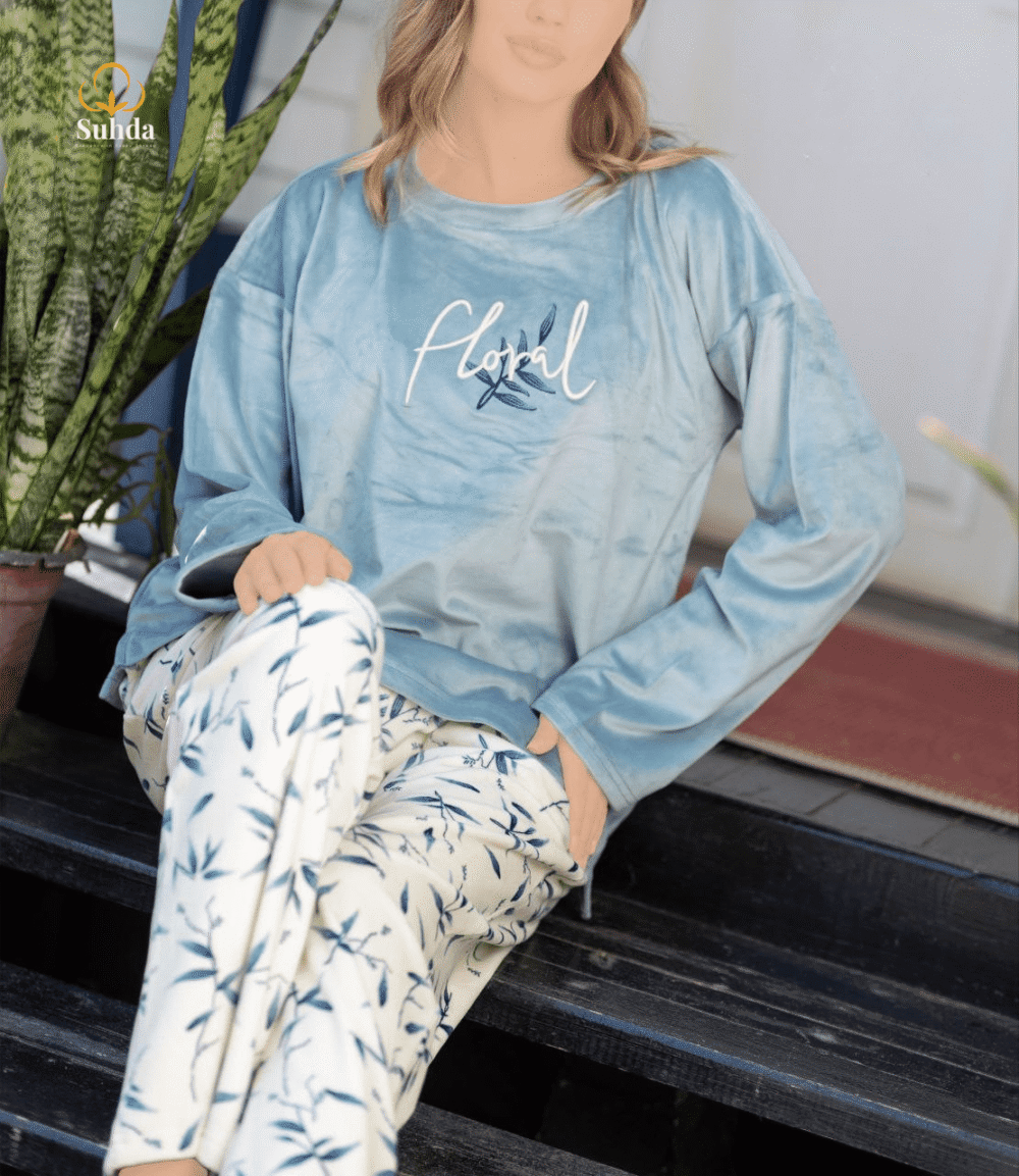 طقم شتوي نسائي بلوزة مخمل سماوية اللون مع بنطال كريمي بنقشة أوراق زرقاء.