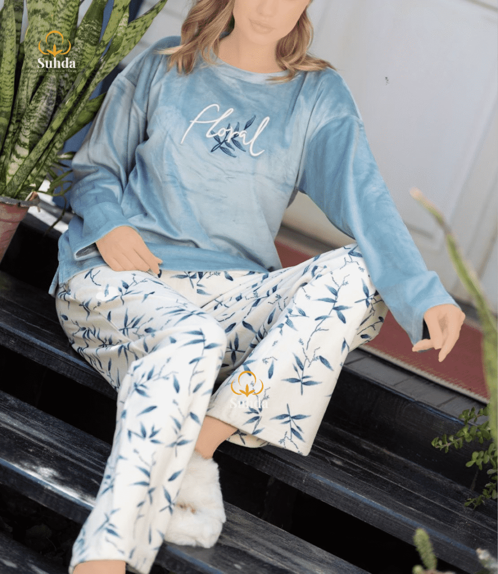 طقم شتوي نسائي بلوزة مخمل سماوية اللون مع بنطال كريمي بنقشة أوراق زرقاء.