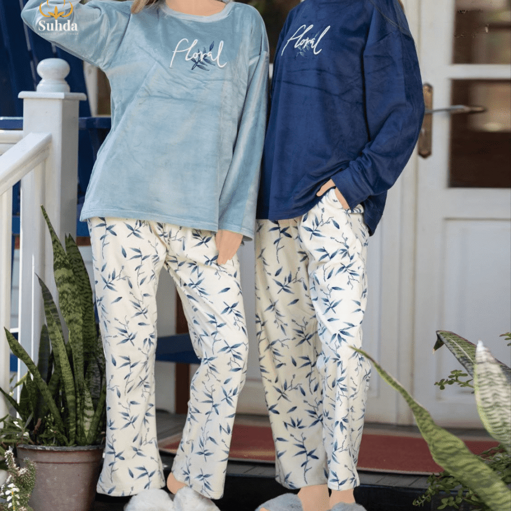 طقم شتوي نسائي بلوزة مخمل سماوية اللون مع بنطال كريمي بنقشة أوراق زرقاء.