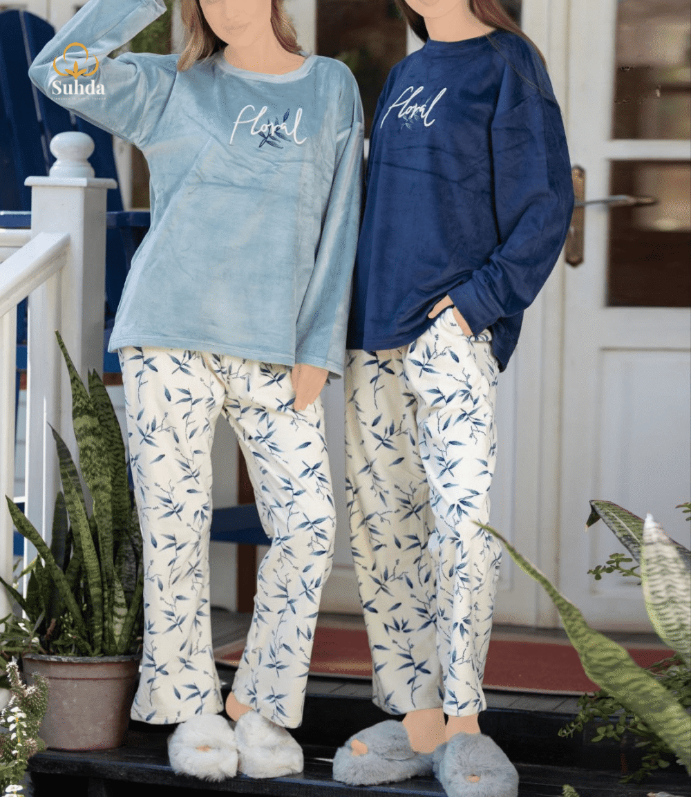 طقم شتوي نسائي بلوزة مخمل سماوية اللون مع بنطال كريمي بنقشة أوراق زرقاء.