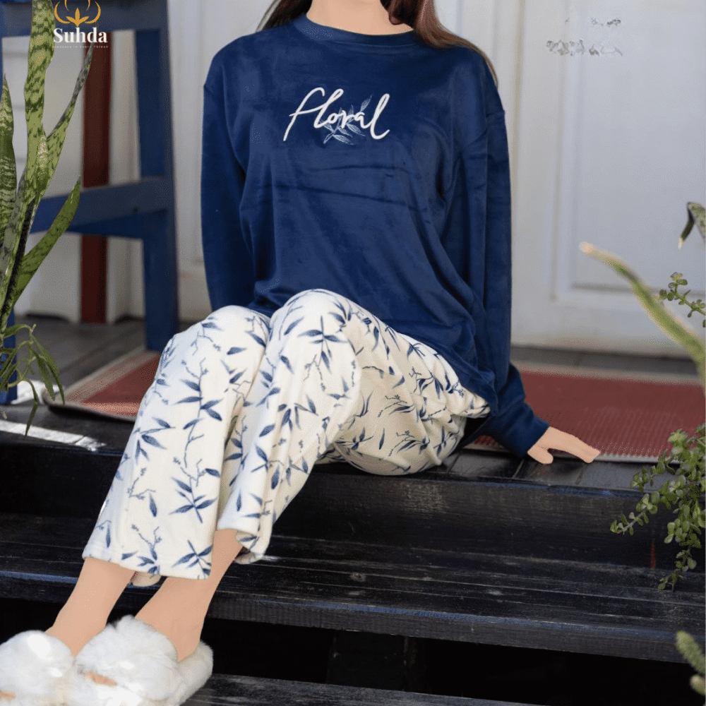 طقم شتوي نسائي بلوزة مخمل سماوية اللون مع بنطال كريمي بنقشة أوراق زرقاء.