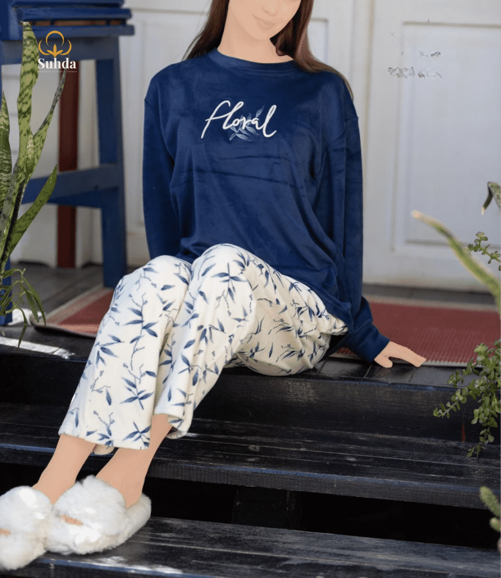 طقم شتوي نسائي بلوزة مخمل سماوية اللون مع بنطال كريمي بنقشة أوراق زرقاء.