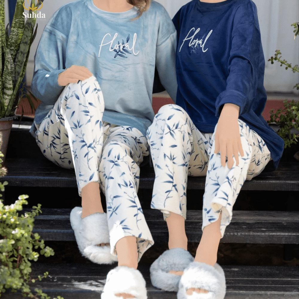 طقم شتوي نسائي بلوزة مخمل سماوية اللون مع بنطال كريمي بنقشة أوراق زرقاء.