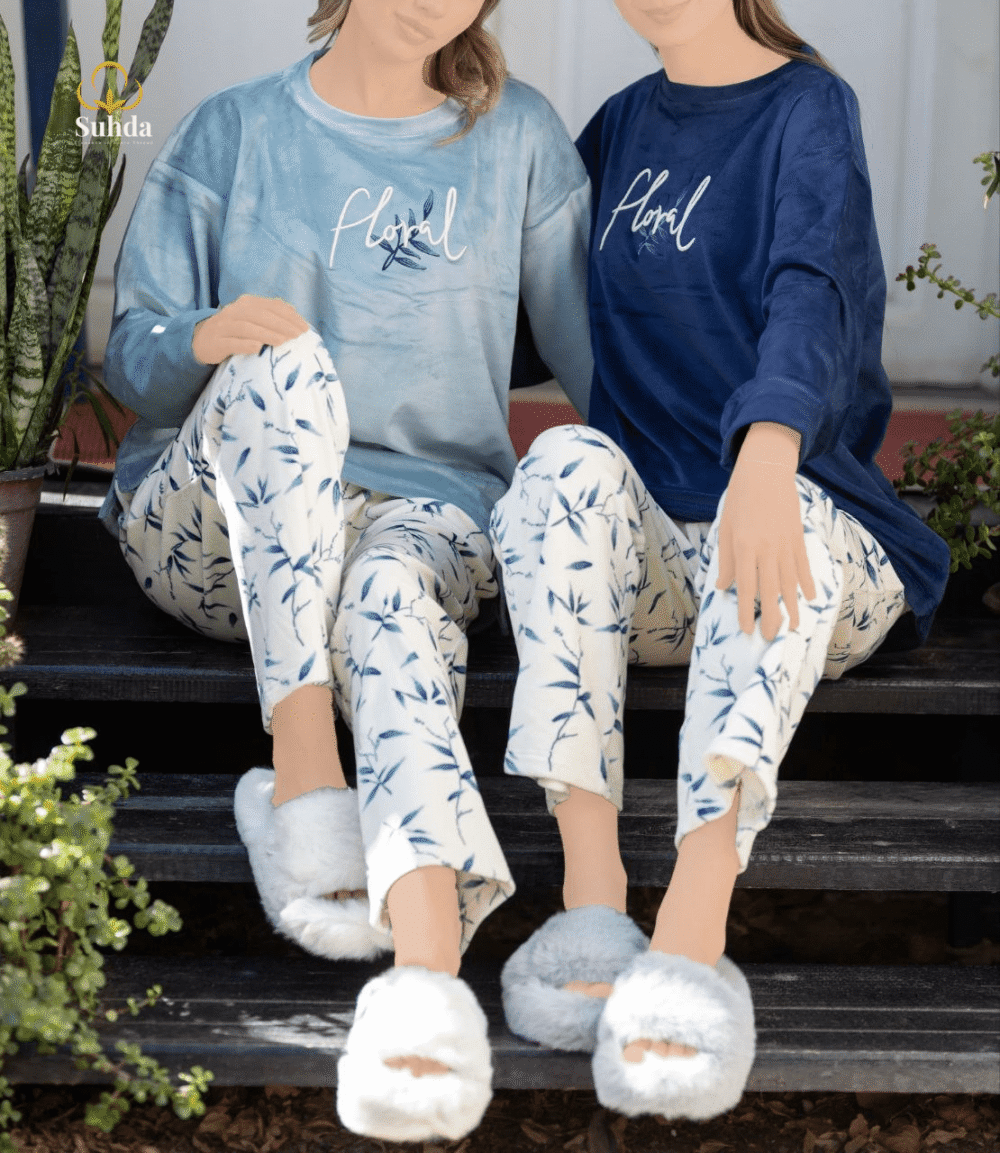 طقم شتوي نسائي بلوزة مخمل سماوية اللون مع بنطال كريمي بنقشة أوراق زرقاء.