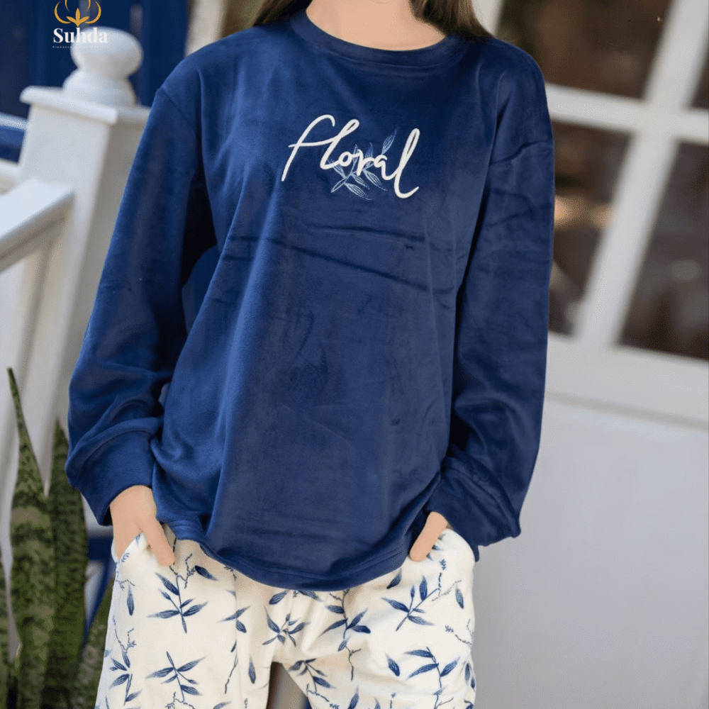 طقم شتوي نسائي بلوزة مخمل سماوية اللون مع بنطال كريمي بنقشة أوراق زرقاء.