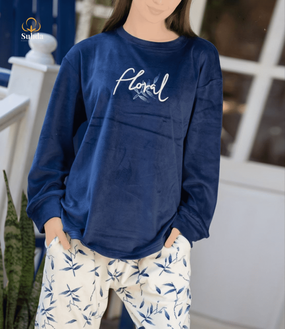 طقم شتوي نسائي بلوزة مخمل سماوية اللون مع بنطال كريمي بنقشة أوراق زرقاء.