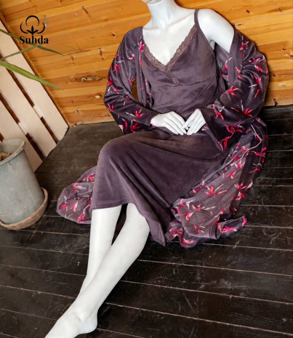 طقم نوم نسائي مخملي بلون بنفسجي داكن يتكون من فستان كت طويل وروب مطبوع بنقشة أوراق وردية.