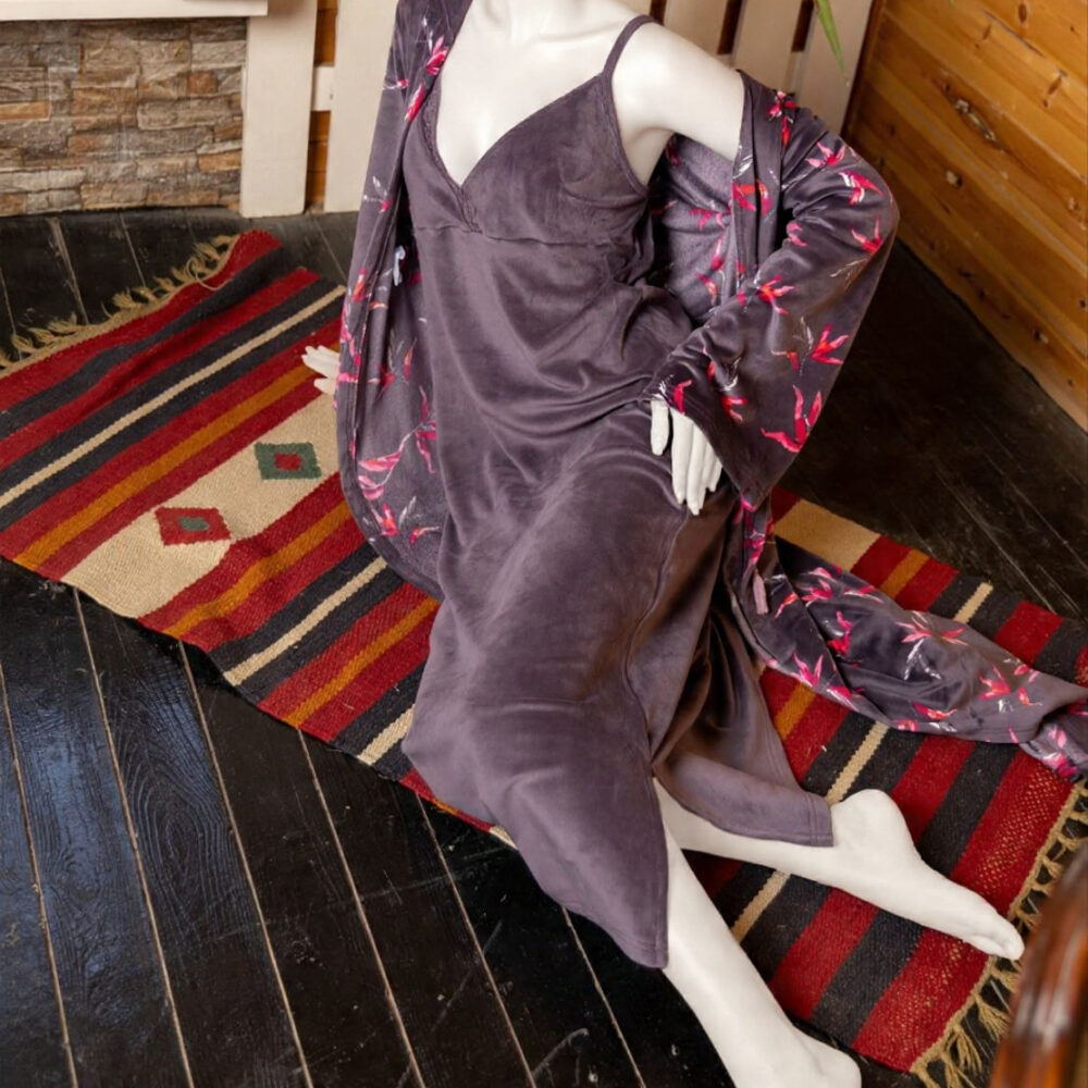 طقم نوم نسائي مخملي بلون بنفسجي داكن يتكون من فستان كت طويل وروب مطبوع بنقشة أوراق وردية.